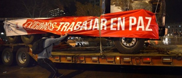 "We Demand to Work in Peace" as a protester rips the sign